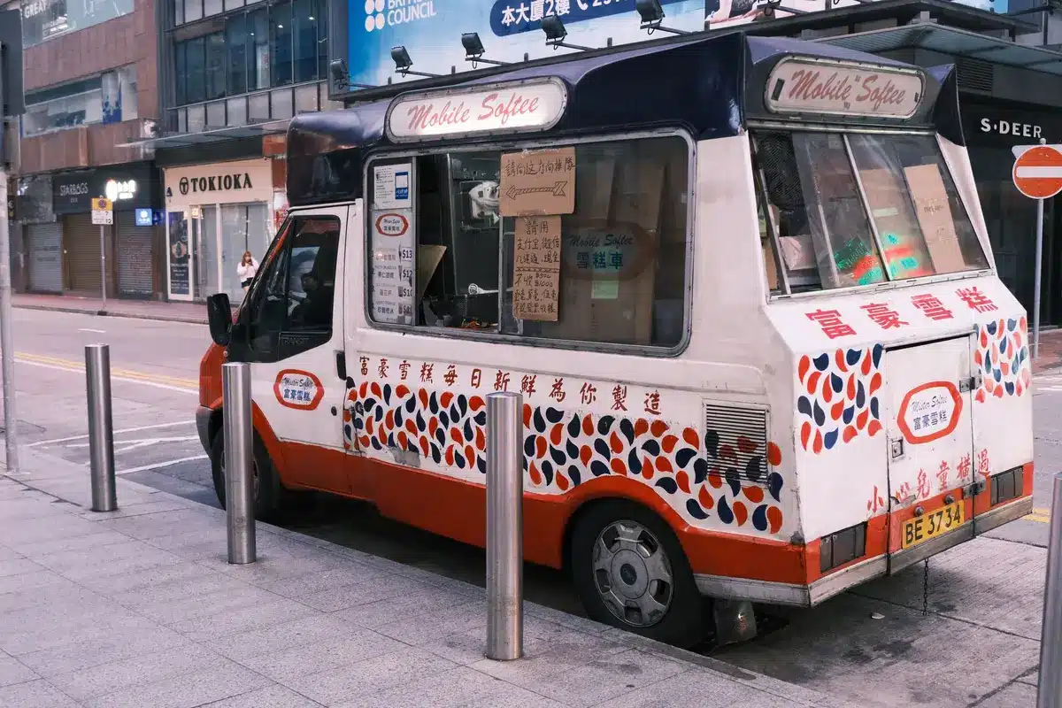 Un camion de glace vintage bleu et blanc garé dans une rue de banlieue déserte sous un ciel crépusculaire