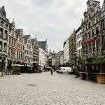 Voyageur à pied dans une place historique européenne avec architecture médiévale et cafés