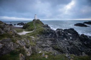 Phare historique en bord de falaise avec sentier et chaussures de randonnée au premier plan
