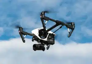 Bâtiment brutaliste en ville avec un drone au-dessus et une main tenant un petit dispositif de données