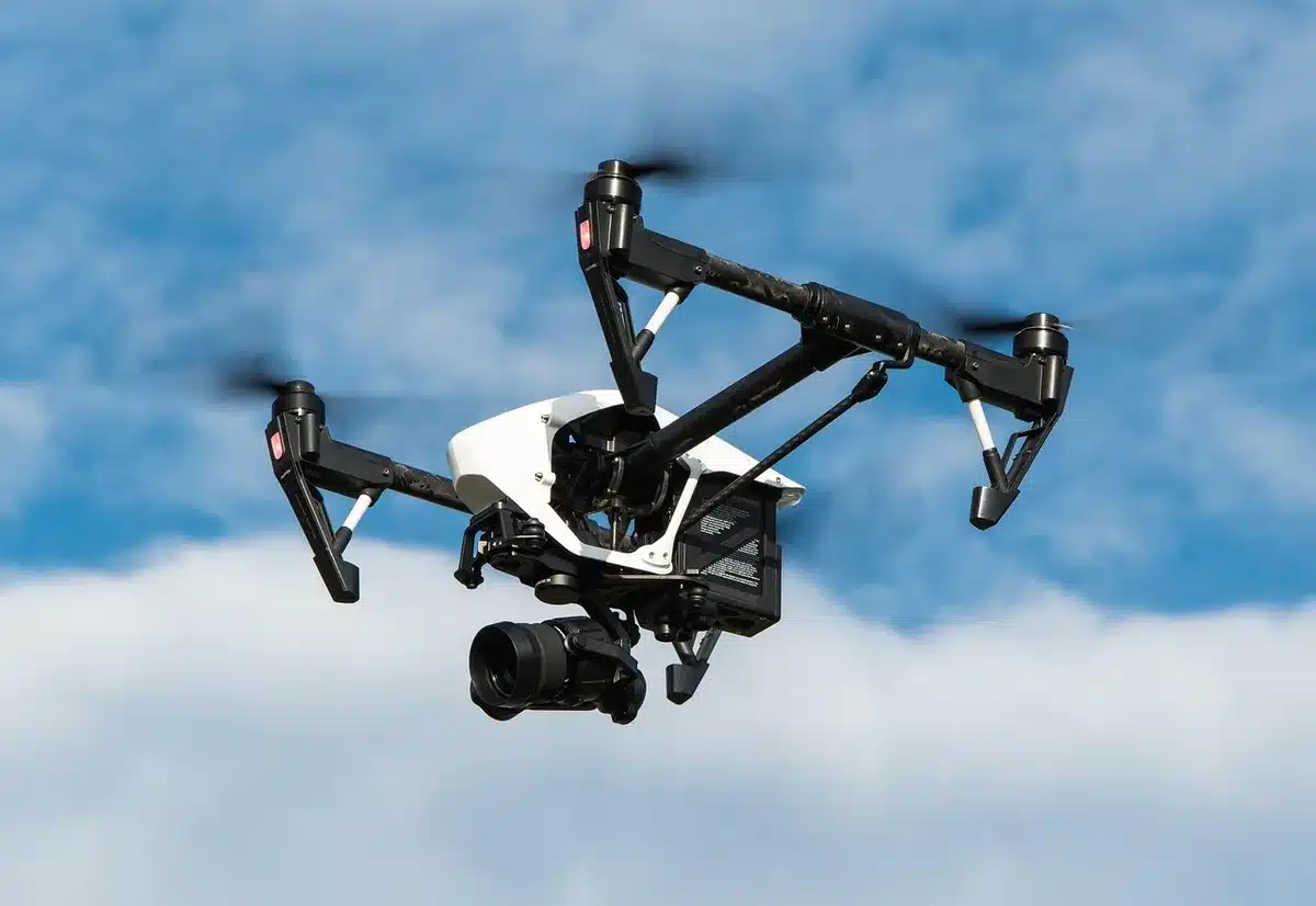 Bâtiment brutaliste en ville avec un drone au-dessus et une main tenant un petit dispositif de données