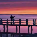 Caméra MiniDV posée sur une rambarde devant une marina au crépuscule