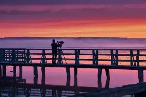 Caméra MiniDV posée sur une rambarde devant une marina au crépuscule